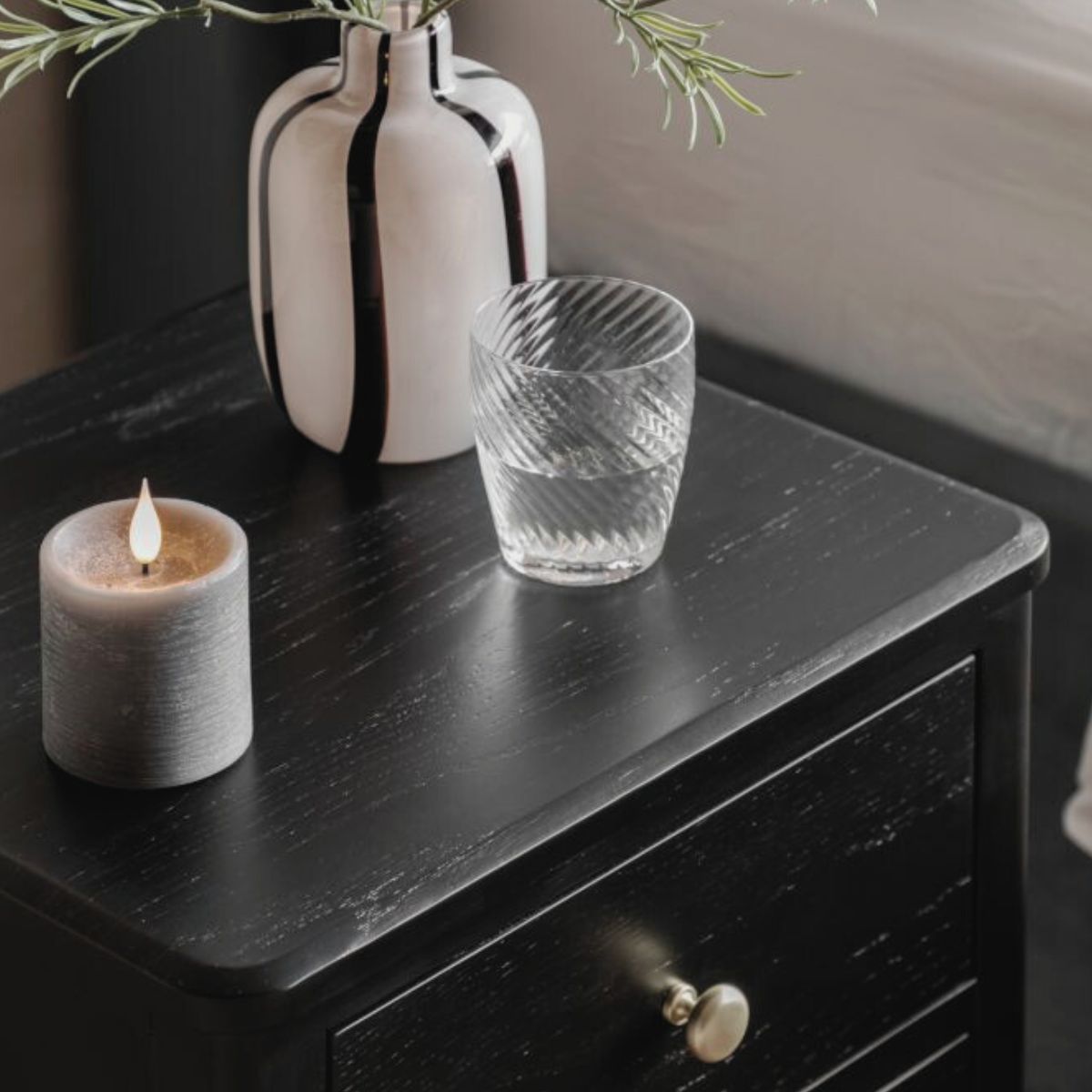 Alvar Black Two Drawer Bedside Table with gold handles and raised base — modern black bedroom furniture by Mallet & Plane.